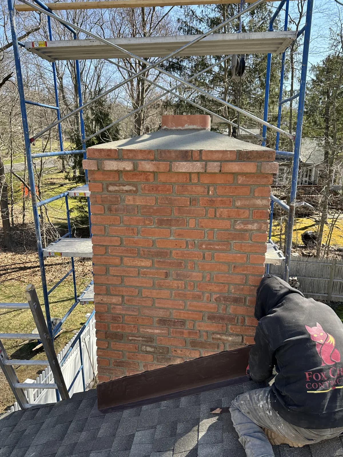 Brick chimney rebuild in progress with new crown and cap on a New Jersey roof