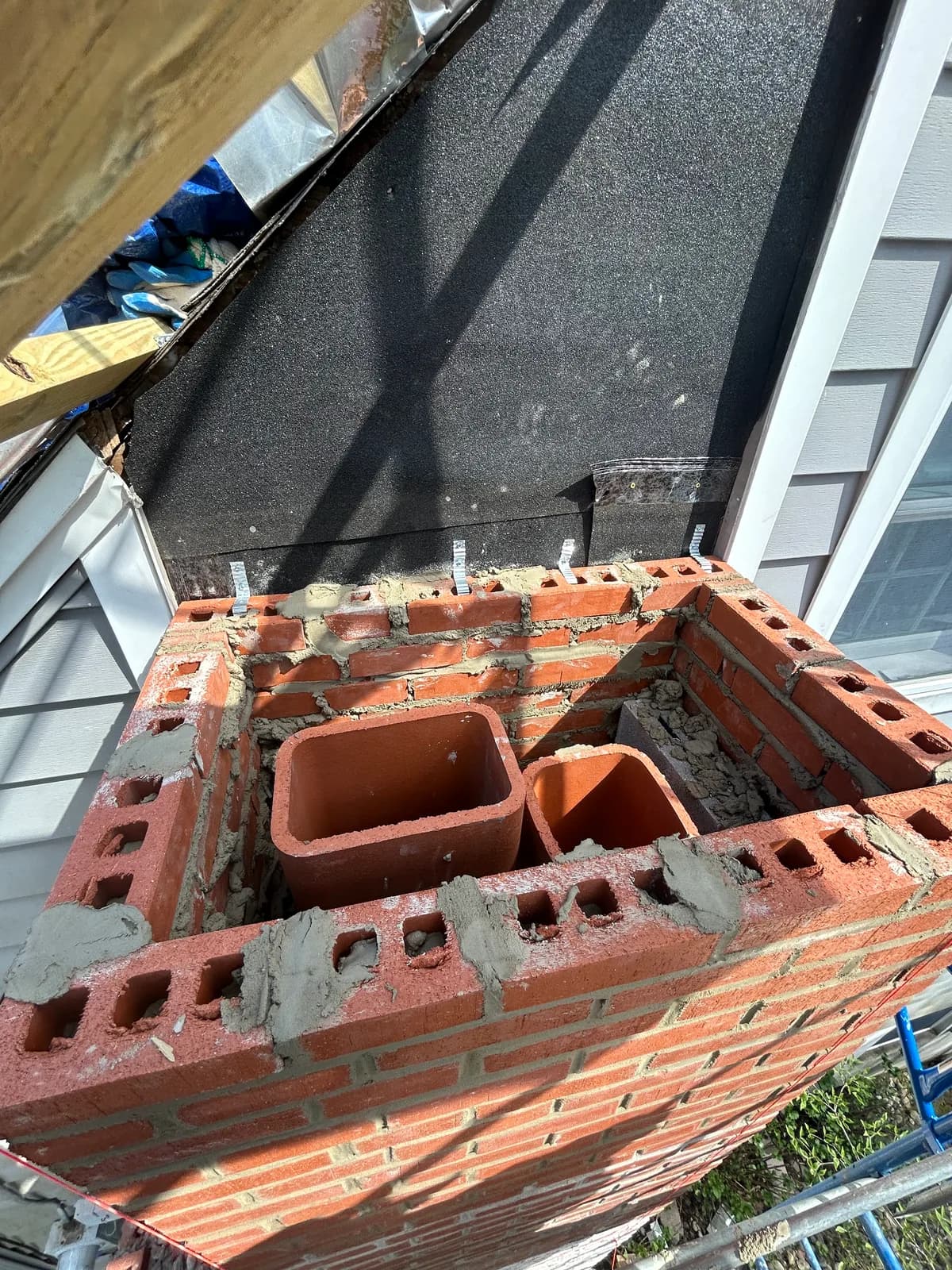 Top of a brick chimney showing new clay flue liners set in fresh mortar