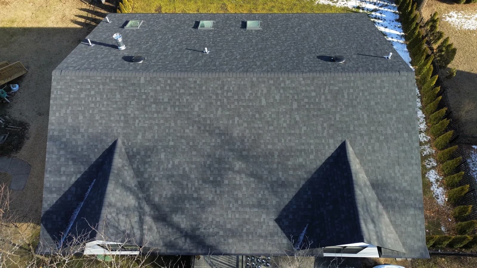 New architectural shingle roof over a white NJ home with a paver patio below